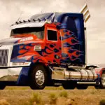A red and blue semi truck with flames on it's side.