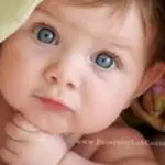 A baby with blue eyes is looking at the camera.