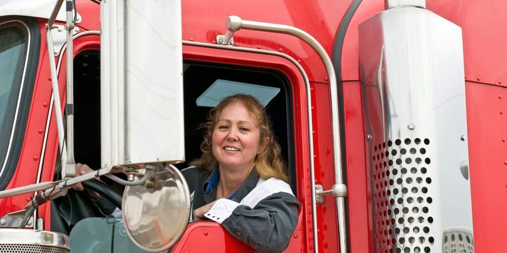A woman sitting in the drivers seat of a red truck.